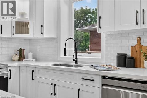 Modern kitchen featuring white shaker cabinetry with black hardware, white subway tile backsplash, and light-toned countertops - 325 Queensdale Avenue E, Hamilton, ON - Indoor Photo Showing Kitchen With Upgraded Kitchen