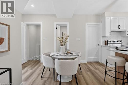 Open-concept dining area featuring wood-finish flooring, a contemporary white dining table, and recessed ceiling lighting - 325 Queensdale Avenue E, Hamilton, ON - Indoor Photo Showing Dining Room