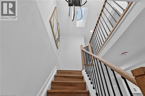 Staircase featuring wood-finish treads, light-toned wood handrails, and black metal balusters - 325 Queensdale Avenue E, Hamilton, ON - Indoor Photo Showing Other Room