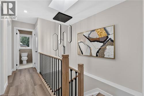 Modern hallway featuring wood-finish flooring and a contemporary linear chandelier - 325 Queensdale Avenue E, Hamilton, ON - Indoor Photo Showing Other Room