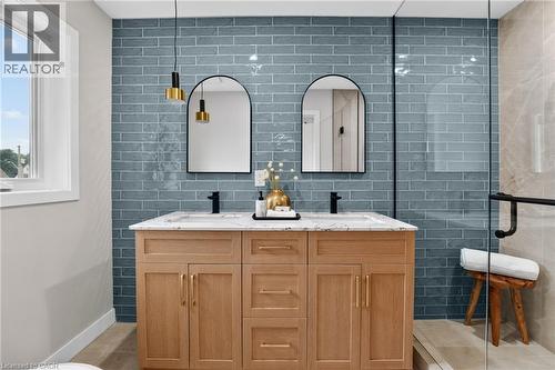 Dual vanity with wood-finish cabinetry, quartz countertop, and matte black fixtures - 325 Queensdale Avenue E, Hamilton, ON - Indoor Photo Showing Bathroom
