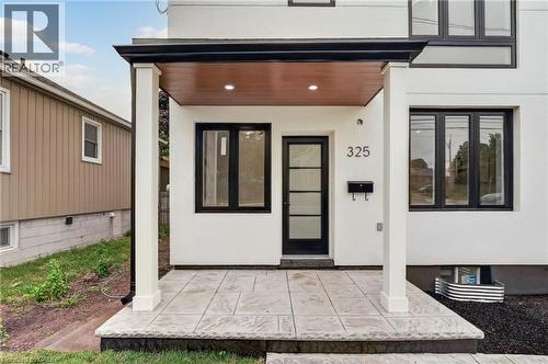 Modern white stucco exterior featuring a covered entryway with a wood-finish ceiling - 325 Queensdale Avenue E, Hamilton, ON - Outdoor With Exterior