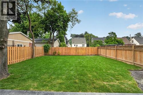 Expansive backyard featuring a lush green lawn, full privacy fencing, mature trees, and a concrete perimeter - 325 Queensdale Avenue E, Hamilton, ON - Outdoor With Backyard