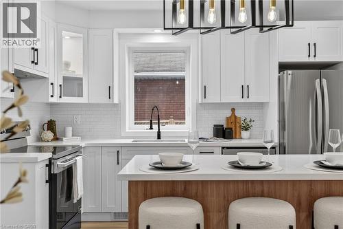 Modern kitchen featuring white shaker cabinetry with black hardware, white subway tile backsplash, and stainless steel appliances - 325 Queensdale Avenue E, Hamilton, ON - Indoor Photo Showing Kitchen With Upgraded Kitchen
