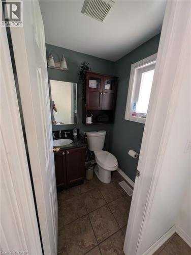 Well-appointed half bath featuring a dark wood vanity with integrated sink, brushed nickel hardware, and ample mirror lighting - 466 Bankside Drive, Kitchener, ON - Indoor Photo Showing Bathroom