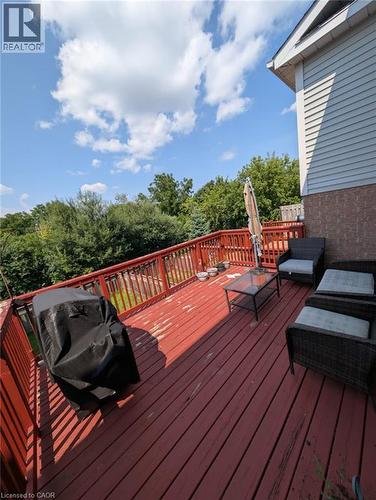 Spacious wooden deck with red stain finish, featuring a full railing system and private tree-lined surroundings - 466 Bankside Drive, Kitchener, ON - Outdoor With Deck Patio Veranda With Exterior