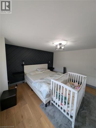 Modern primary bedroom featuring a geometric black shiplap accent wall, recessed ceiling lighting, wood-finish flooring, and ample space for bedroom furnishings - 466 Bankside Drive, Kitchener, ON - Indoor Photo Showing Bedroom