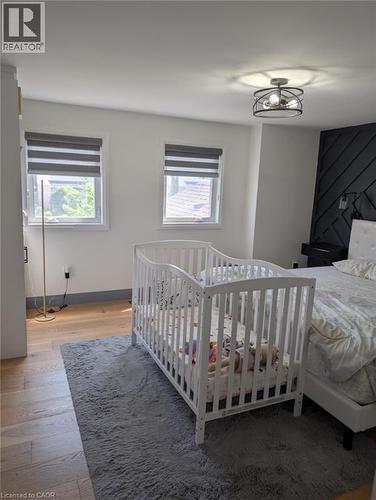 Bright secondary bedroom featuring hardwood flooring, two large double-hung windows with cellular shades providing natural light, and a ceiling-mounted fixture - 466 Bankside Drive, Kitchener, ON - Indoor Photo Showing Bedroom
