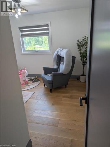 Bright upper-level room featuring wood-finish flooring, a large window with cellular shade, ceiling fan with integrated lighting, and clean white walls - 466 Bankside Drive, Kitchener, ON - Indoor Photo Showing Other Room