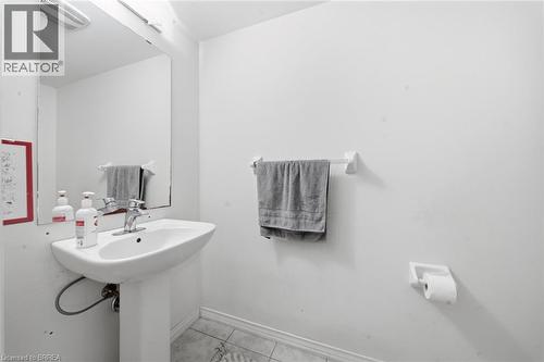 Pedestal sink with chrome faucet, wall-mounted mirror, and tile flooring - 32 Cole Crescent, Brantford, ON - Indoor Photo Showing Bathroom
