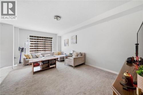 Carpeted living area featuring light gray walls and a large window with horizontal blinds - 32 Cole Crescent, Brantford, ON - Indoor