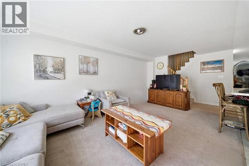Carpeted living area featuring white walls, a built-in media console, and a staircase with wood railing - 32 Cole Crescent, Brantford, ON - Indoor Photo Showing Living Room
