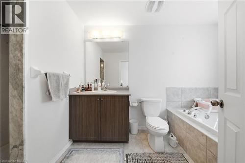 Bathroom featuring a wood-finish vanity with an integrated sink, a large mirror, and an overhead light fixture - 32 Cole Crescent, Brantford, ON - Indoor Photo Showing Bathroom