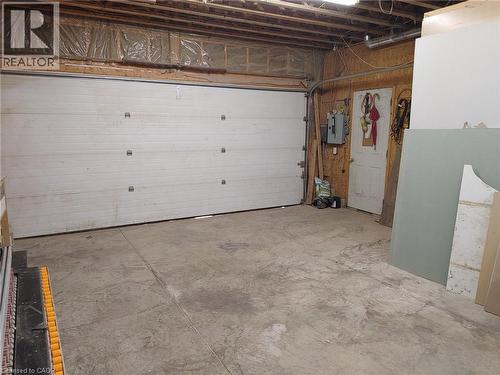 Garage interior featuring a sectional garage door, exposed ceiling joists, and concrete flooring - 76 Brentwood Avenue, Kitchener, ON - Indoor Photo Showing Garage