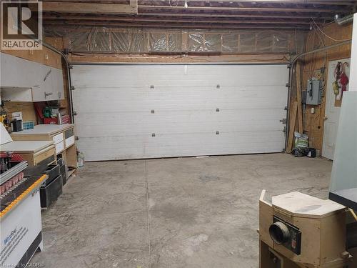 Spacious garage with a large white sectional door, exposed ceiling joists, concrete flooring, and built-in wood cabinetry - 76 Brentwood Avenue, Kitchener, ON - Indoor Photo Showing Garage