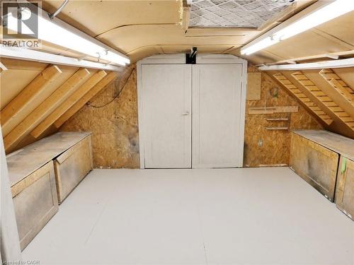 Versatile loft space featuring sloped wood-finish ceilings, white painted flooring, and a double-door entry to the other side of loft space - 76 Brentwood Avenue, Kitchener, ON - Indoor