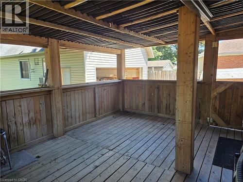 Covered wooden deck lower deck off the kitchen area featuring wood plank flooring, matching wood railing with open sections, and a corrugated metal roof - 76 Brentwood Avenue, Kitchener, ON - Outdoor With Deck Patio Veranda With Exterior