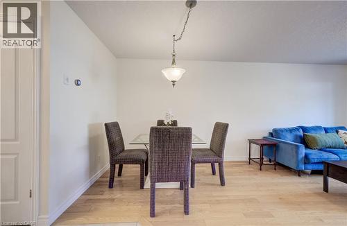 Dining area featuring wood-finish flooring, a contemporary ceiling light fixture, and a white paneled door - 496 Langlaw Drive, Cambridge, ON - Indoor Photo Showing Dining Room