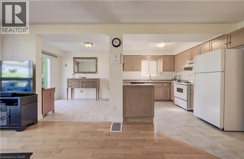 Open-concept kitchen with light-toned cabinetry, white appliances, and a double-basin stainless steel sink - 496 Langlaw Drive, Cambridge, ON - Indoor Photo Showing Kitchen