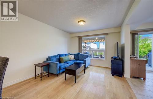 Spacious living area featuring light wood-finish flooring, neutral wall tones, and a window with exterior pergola structure - 496 Langlaw Drive, Cambridge, ON - Indoor Photo Showing Living Room