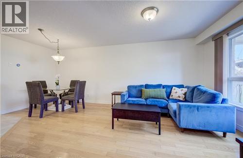 Open-concept living area with light wood-finish flooring, white wall tones, a large window, a ceiling-mounted light fixture, and a pendant light fixture - 496 Langlaw Drive, Cambridge, ON - Indoor