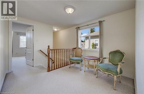 Carpeted landing area featuring a wooden staircase railing, a white window frame, and neutral wall paint - 496 Langlaw Drive, Cambridge, ON - Indoor Photo Showing Other Room