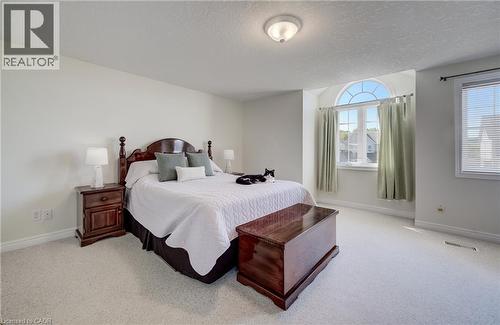 Room featuring light-colored carpeting, a large arched window, a secondary rectangular window, and a ceiling-mounted light fixture - 496 Langlaw Drive, Cambridge, ON - Indoor Photo Showing Bedroom
