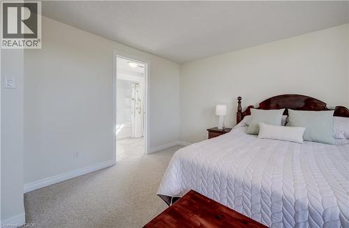 Carpeted room featuring light-toned walls and trim, with a doorway opening to a tiled bathroom space - 496 Langlaw Drive, Cambridge, ON - Indoor Photo Showing Bedroom