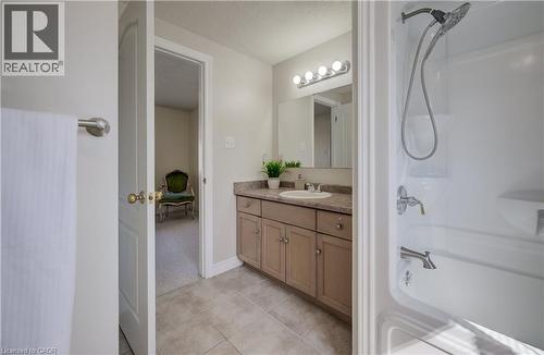 Bathroom featuring a white shower/tub combination with a chrome showerhead, a single-sink vanity with a light brown countertop, and tile flooring - 496 Langlaw Drive, Cambridge, ON - Indoor Photo Showing Bathroom