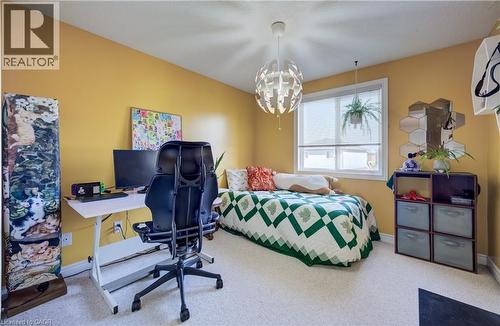Bright room featuring a single window with blinds, carpet flooring, a decorative ceiling light fixture, and a built-in shelving unit - 496 Langlaw Drive, Cambridge, ON - Indoor Photo Showing Bedroom