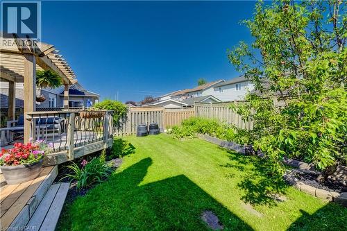 Expansive backyard featuring a multi-level wooden deck with pergola, manicured lawn, perimeter fencing, mature trees, and landscaping elements - 496 Langlaw Drive, Cambridge, ON - Outdoor With Deck Patio Veranda