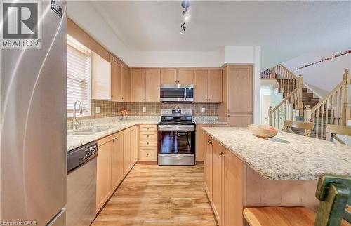 Kitchen featuring wood-finish flooring, light wood cabinetry, granite countertops, and stainless steel appliances - 521 Snowdrop Court, Kitchener, ON - Indoor Photo Showing Kitchen