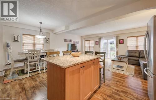Open-concept living space featuring wood-finish flooring, a kitchen island with stone-finish countertop, and a dining area with pendant lighting - 521 Snowdrop Court, Kitchener, ON - Indoor