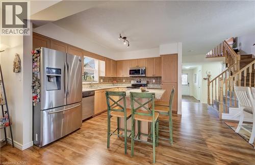 Kitchen featuring wood-finish flooring, light wood cabinetry, stainless steel appliances, and a central island with a stone-finish countertop - 521 Snowdrop Court, Kitchener, ON - Indoor Photo Showing Kitchen