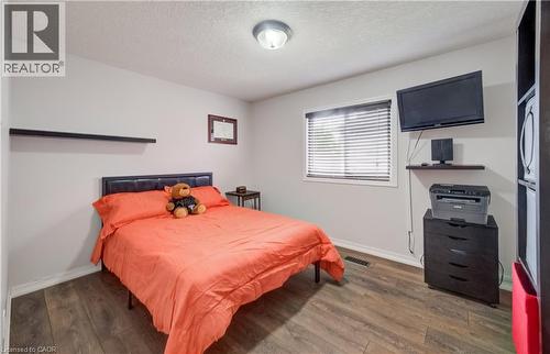 Interior room featuring wood-finish flooring, light gray wall paint, and a window with horizontal blinds - 521 Snowdrop Court, Kitchener, ON - Indoor Photo Showing Bedroom