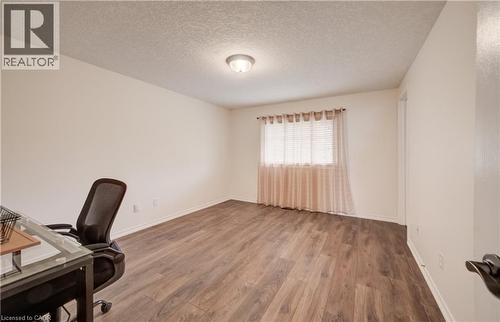 Room featuring wood-finish flooring, a single window with blinds and sheer curtains, and a flush-mount ceiling light - 521 Snowdrop Court, Kitchener, ON - Indoor Photo Showing Office