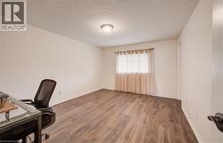Room featuring wood-finish flooring, a single window with blinds and sheer curtains, and a flush-mount ceiling light - 