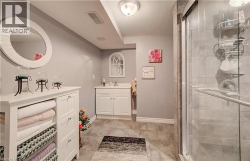 Bathroom featuring a white vanity with an integrated sink, a glass-enclosed shower with tiled walls, and stone-look tile flooring - 521 Snowdrop Court, Kitchener, ON - Indoor Photo Showing Bathroom