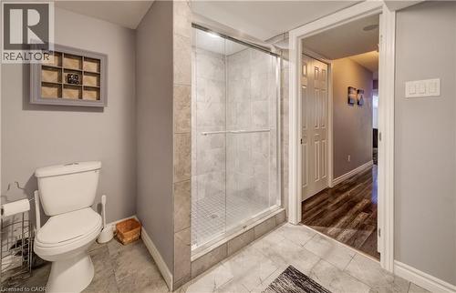 Three-piece bathroom featuring a glass-enclosed shower with tiled walls, a standard toilet, and large format tiled flooring - 521 Snowdrop Court, Kitchener, ON - Indoor Photo Showing Bathroom