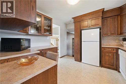 Warm wood cabinetry and countertops define this spacious kitchen, featuring ample storage with upper and lower cabinets, a center island with seating space, and stainless steel appliances. - 18 Strathcona Crescent, Kitchener, ON - Indoor Photo Showing Kitchen