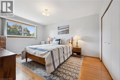Bright bedroom with hardwood flooring, a large window, and a built-in closet with bi-fold doors - 18 Strathcona Crescent, Kitchener, ON - Indoor Photo Showing Bedroom
