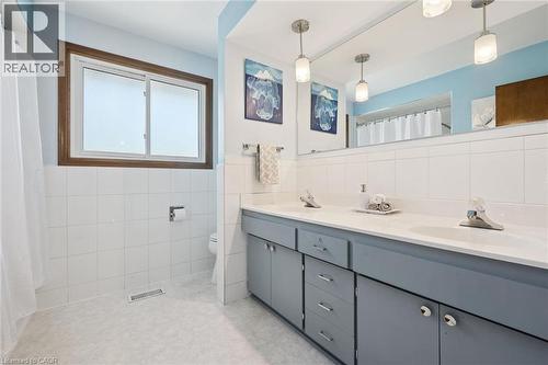 Double vanity with gray cabinetry and integrated sinks, complemented by a large wall-mounted mirror - 18 Strathcona Crescent, Kitchener, ON - Indoor Photo Showing Bathroom