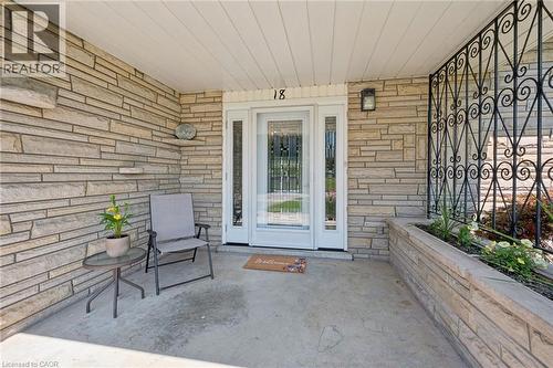 Stone veneer exterior featuring a covered entry, white door with sidelights, built-in planter, and decorative metalwork - 18 Strathcona Crescent, Kitchener, ON - Outdoor With Deck Patio Veranda