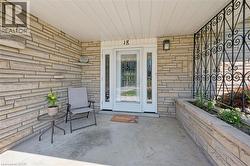 Stone veneer exterior featuring a covered entry, white door with sidelights, built-in planter, and decorative metalwork - 