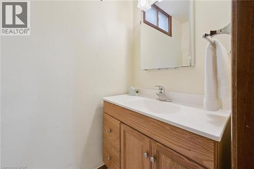 Bathroom vanity featuring a light wood-finish cabinet with silver hardware, an integrated white sink, a chrome faucet, and a wall-mounted mirror - 18 Strathcona Crescent, Kitchener, ON - Indoor Photo Showing Bathroom