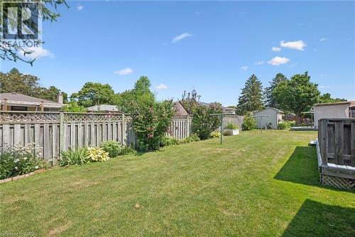 Spacious backyard featuring a manicured lawn, established perimeter fencing, mature trees, and a storage shed - 18 Strathcona Crescent, Kitchener, ON - Outdoor With Backyard