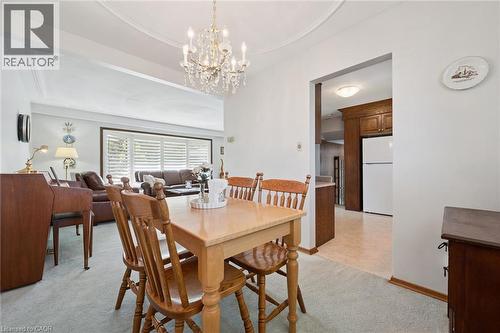 Bright open-concept dining and living area anchored by a solid wood dining table with matching spindle-back chairs - 18 Strathcona Crescent, Kitchener, ON - Indoor Photo Showing Dining Room