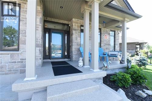 Welcoming front entry showcasing a substantial stone and brick exterior with white columns, a black front door with sidelights, and a covered portico - 10 Craddock Boulevard, Jarvis, ON - Outdoor