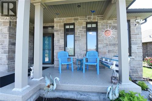 Covered front porch featuring fluted columns, stone exterior, and a blue glass entry door - 10 Craddock Boulevard, Jarvis, ON - Outdoor With Deck Patio Veranda
