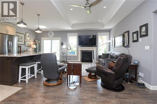 Open-concept living area featuring coffered ceiling with recessed lighting and ceiling fan, wood-finish flooring throughout, and a gas fireplace with built-in cabinetry - 10 Craddock Boulevard, Jarvis, ON - Indoor With Fireplace